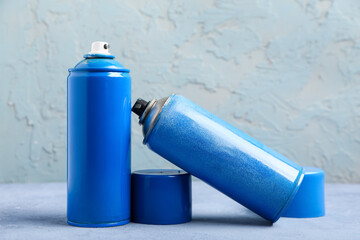 Spray cans with blue paint on color table