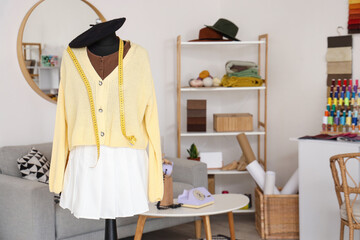 Mannequin with stylish clothes and tape measure in fashion designer's studio