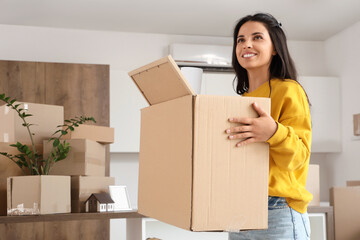 Beautiful woman carrying box in kitchen on moving day