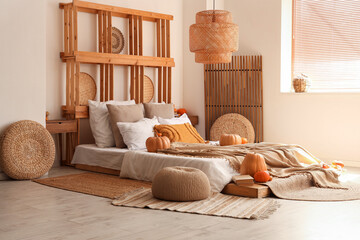 Interior of cozy bedroom with autumn decor and poufs