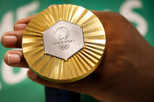 Gold medal of Paris 2024 Olympic Games handheld. Detail shot of Summer Olympics medal, sports competition winner symbol.