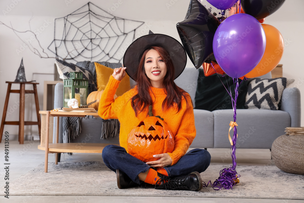 Canvas Prints Young Asian woman in witch hat with Halloween pumpkin and balloons at home