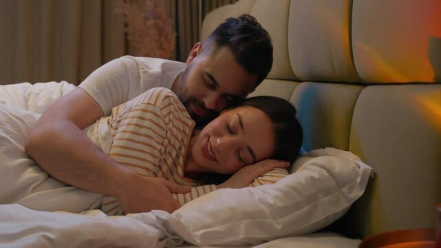 Caucasian happy couple love lying bed together kiss hugging cozy pleasure smile woman man girlfriend boyfriend wife husband honeymoon sweetheart tenderness sleep night female male bedroom home comfort