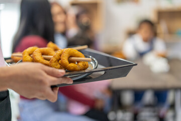 Waiter holding tray with peruvian picarones donuts in cafe