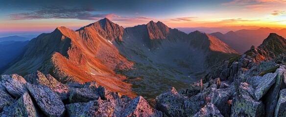 Obraz premium Panoramic view of the Tatra Mountains at sunset, showcasing rugged peaks, craggy cliffs, and dramatic rocky terrain.