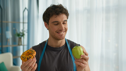 Caucasian man holding apple donut healthy junk food nutrition guy snack athlete bodycare think...