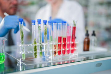 scientists perform experiments and record data. people arranges equipment with test tubes and chemicals for producing medicine and biochemistry. man hold tubes of chemical liquids and plant samples.