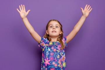 A young girl looks upwards with her hands held high, possibly in excitement or celebration