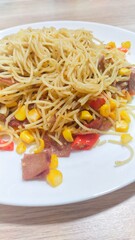 Homemade recipe classic aglio e olio pasta with smoked beef and corn, close-up in a white plate on the table