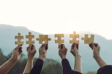 Concept of teamwork and partnership. Business teamwork joins puzzle pieces into the sky with...
