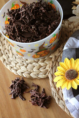 Homemade Chocolate Stick Candy with Sparkling Sugar in a Festive Halloween Bucket with Light Pastries on Wicker Placemats with Sunflower and Buffalo Check Decor
