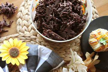 Homemade Chocolate Stick Candy with Sparkling Sugar in a Festive Halloween Bucket with Light Pastries on Wicker Place Mats with Sunflower and Buffalo Check Decor
