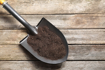 Metal shovel with soil on wooden table, top view. Space for text