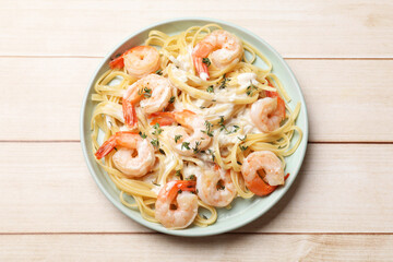 Delicious pasta with shrimps and creamy sauce on light wooden table, top view