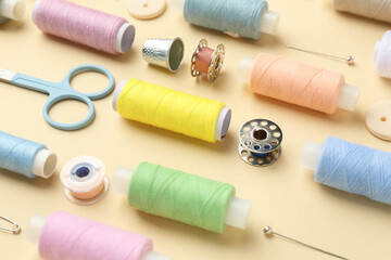 Different sewing supplies on beige background, closeup