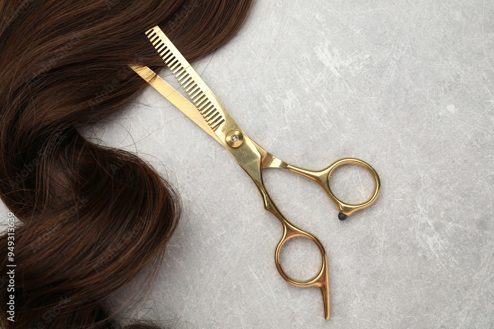 Wall mural brown hair strand and professional scissors on grey table, top view