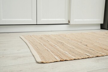 Stylish soft rug on wooden floor in kitchen