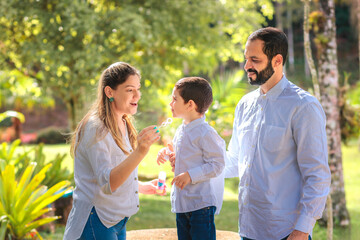 A happy family enjoys a sunny day outdoors, blowing bubbles and creating fun memories. A joyful, carefree moment that captures love, connection, and togetherness in nature.