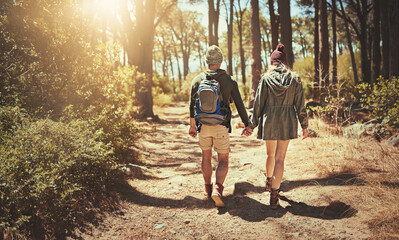 Fototapeta premium Back, couple and holding hands for hiking outdoor with backpack, trekking path and travel adventure in nature. People, support and backpacking for fitness, health bonding and cardio care in forest