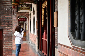 Taiwan - Jan 17, 2024: A female devotee holding incense and praying in a quiet corner of Taipei Bao An Temple during the day, reflecting traditional spiritual practice.