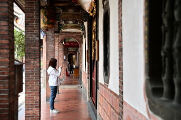 Obraz premium Taiwan - Jan 17, 2024: A female devotee holding incense and praying in a quiet corner of Taipei Bao An Temple during the day, reflecting traditional spiritual practice.