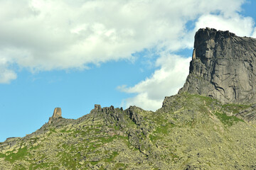 View of a high ridge of steep rocks with pointed stone peaks on a sunny summer day.