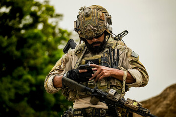 Fototapeta premium A group of military men in combat gear patrol in the middle of a desert and tropical jungle. Soldiers in full combat gear in dry weather conditions assemble and march on a mission.