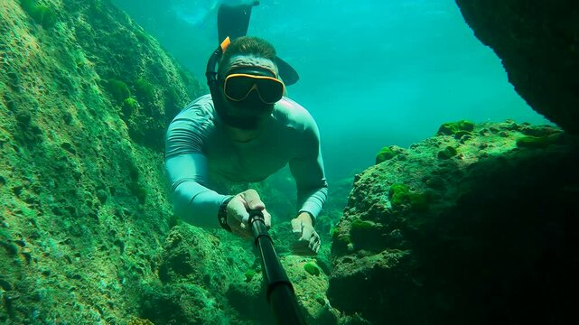Beautiful corals, fish and underwater life of the Andaman Sea, underwater shooting off the coast of Racha Noi Island, a man films himself while scuba diving