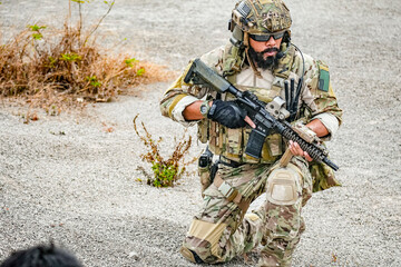 A group of military men in combat gear patrol in the middle of a desert and tropical jungle....