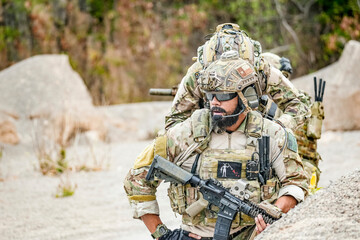 A group of military men in combat gear patrol in the middle of a desert and tropical jungle....