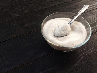 sugar in a bowl on the black wooden table. Food ingredient 