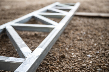 A metal structure with a triangular shape is sitting on a dirt field.