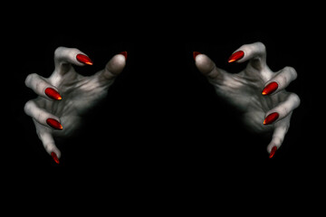Deadly hands of vampire or monster with sharp bloody red nails in the dark. Witchy fingers hold something invisible, low key, selected focus.