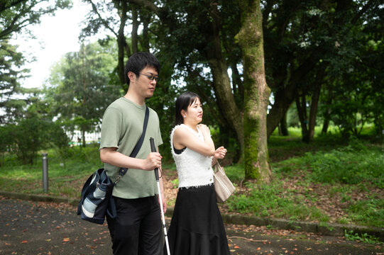 目が見えない日本人男性が白杖をつきながら森の中を散策している