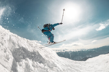 Fast and professional skier jumps at big speed from snowdrift high in mountains