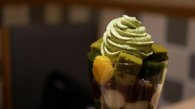 close up view to beautiful parfait sweet dessert in japanese style full with ice cream mochi green tea yelly and topped with green tea cream in japanese minimal cafe