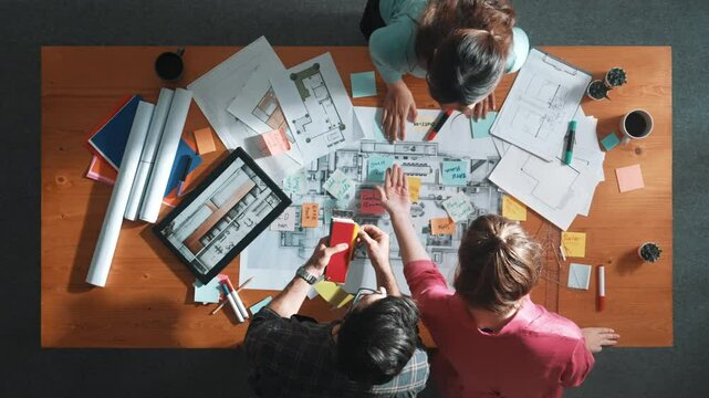 Top view of engineer working together to design building construction while standing at meeting table with blueprint and notes. Top view of interior designer choosing color from palettes. Symposium.