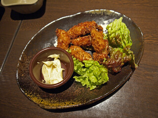 Ceramic Plate of Japanese deep fried crispy kakifrai oysters with green salad and white mayonnaise sauce on izakaya restaurant table