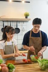 Happy young couple preparing meal together in a kitchen. Cooking and healthy living concept