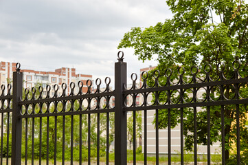Metal fence in the city park. Decorative black iron guardrail for protection, close up