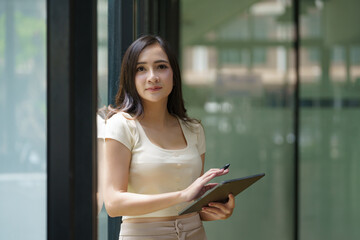 Asian businesswoman standing and holding a digital tablet.