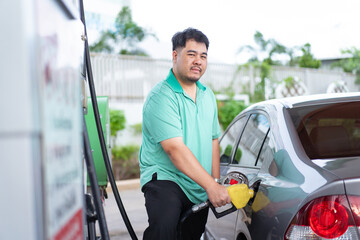 Asian man is refuels his car a gas.