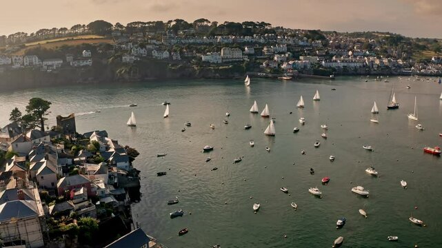 Aerial drone shot of coastal town of Fowey in Cornwall, UK at golden hour. Picturesque view of the small sailing boats