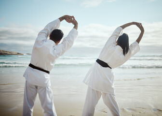 Stretching, martial arts and people at beach for team training, flexible or back view. Ocean, karate and couple warm up for fight, fitness and warrior prepare healthy body for exercise lesson outdoor © Flashizzle/peopleimages.com
