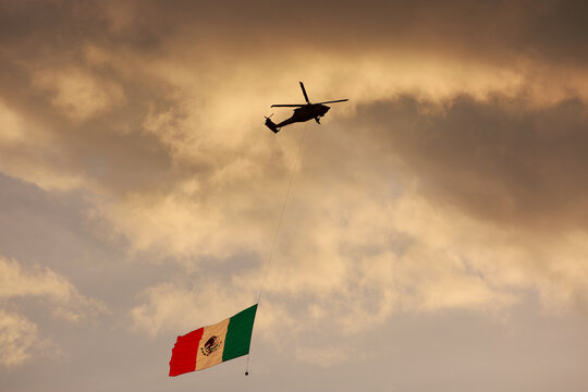 Ciudad de Mexico, Mexico - November 30. 2023: Helicopter in flight shows a Mexican Flag to people on the ground