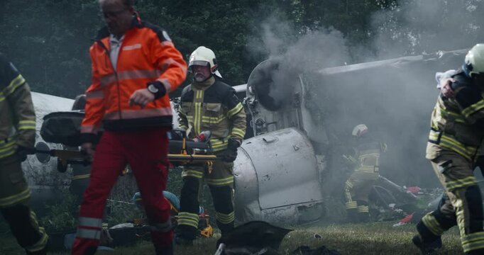 Forest Is Alive with Activity of Rescue Teams, as Firefighters Battle Lingering Flames and Paramedics Assist Injured Passengers at an Airplane Crash Site. Cinematic Footage of a Chaotic Wreckage