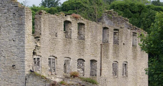 mid shot of dialect stone buildings next to Peakshole water stream in the hope valley, Castleton.
