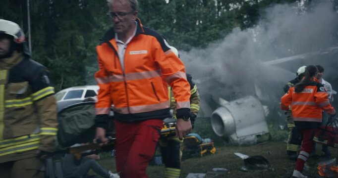 Rescue Team Working on Wreckage Site of a Crashed Airliner, Firefighters Extinguishing Flames while Paramedics Attend to Injured Passengers. Follow Footage of a Female Medic Running to Save Lives