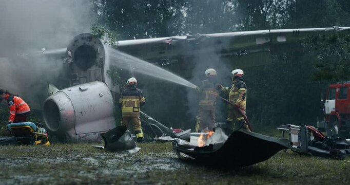 Plane Crash After a Horrific Terrorist Attack: Firefighters Work to Control the Flames while Paramedics Tend to the Injured Victims. Rescue Team Determined to Save Every Passenger in Heavy Rain