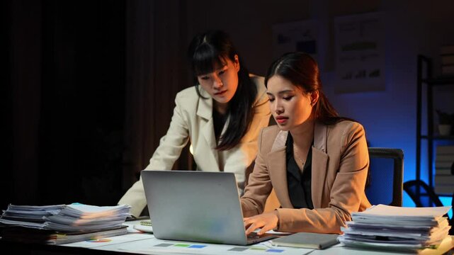 Two businesswomen are tired, stressed, and have headaches over a failed business. while sitting in front of a laptop Working in finance online, office syndrome concept.